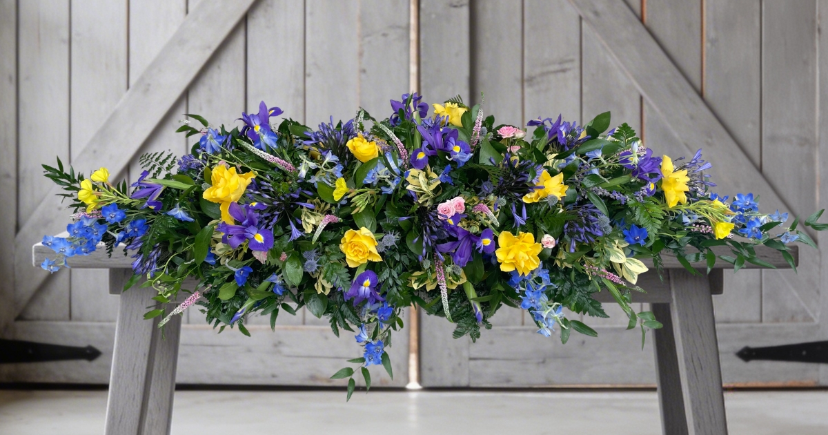 Yellow and blue coffin spray by Beloved Flowers, Kent